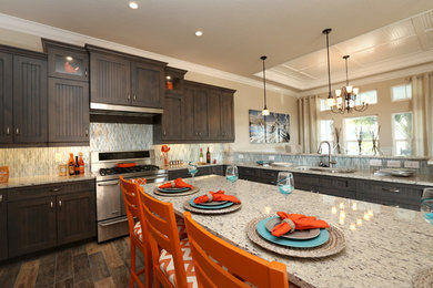 Eat-in kitchen - mid-sized coastal u-shaped porcelain tile and multicolored floor eat-in kitchen idea in Jacksonville with a double-bowl sink, beaded inset cabinets, gray cabinets, granite countertops, metallic backsplash, glass tile backsplash, stainless steel appliances and an island
