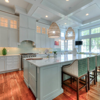 Open concept kitchen - coastal medium tone wood floor and brown floor open concept kitchen idea in Philadelphia with an undermount sink, shaker cabinets, white cabinets, green backsplash, glass tile backsplash, stainless steel appliances, an island and white countertops