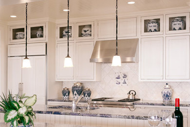 Inredning av ett klassiskt kök, med en undermonterad diskho, luckor med infälld panel, vita skåp, marmorbänkskiva, vitt stänkskydd, stänkskydd i keramik, integrerade vitvaror och ljust trägolv