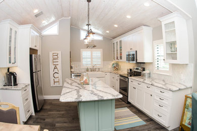 Inspiration for a mid-sized coastal u-shaped dark wood floor open concept kitchen remodel in Tampa with a farmhouse sink, white cabinets, white backsplash, stainless steel appliances, an island, shaker cabinets, marble countertops and porcelain backsplash