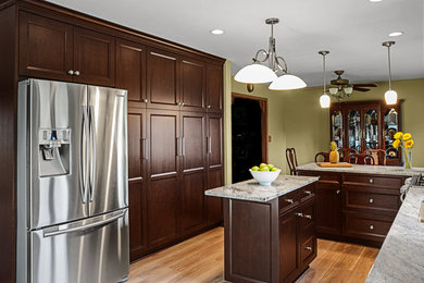 Eat-in kitchen - large traditional u-shaped medium tone wood floor eat-in kitchen idea in Other with an undermount sink, shaker cabinets, dark wood cabinets, granite countertops, white backsplash, subway tile backsplash, stainless steel appliances and an island