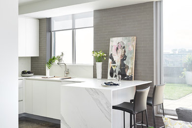 Small modern u-shaped enclosed kitchen in Toronto with a submerged sink, flat-panel cabinets, white cabinets, engineered stone countertops, white splashback, marble splashback, stainless steel appliances, dark hardwood flooring, a breakfast bar, brown floors and white worktops.
