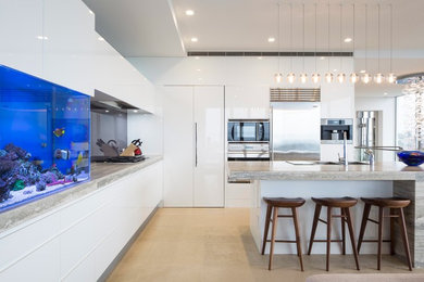 Inspiration for a large contemporary galley kitchen/diner in Other with a submerged sink, white cabinets, limestone worktops, glass sheet splashback, stainless steel appliances and an island.