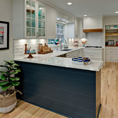 Mid-sized beach style u-shaped light wood floor kitchen photo in Minneapolis with an undermount sink, white cabinets, quartz countertops, white backsplash, subway tile backsplash, stainless steel appliances, a peninsula, white countertops and shaker cabinets