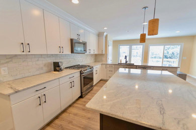 Example of a large galley eat-in kitchen design in Cleveland with white backsplash and two islands