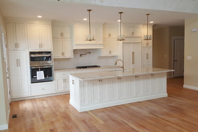 ボストンにある高級な中くらいなトランジショナルスタイルのおしゃれなキッチン (アンダーカウンターシンク、インセット扉のキャビネット、白いキャビネット、御影石カウンター、白いキッチンパネル、サブウェイタイルのキッチンパネル、パネルと同色の調理設備、無垢フローリング、茶色い床、マルチカラーのキッチンカウンター) の写真