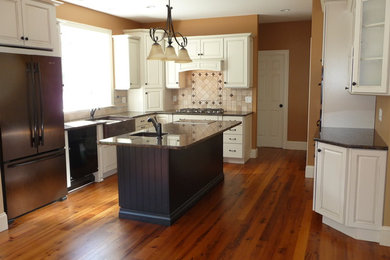 Mid-sized minimalist u-shaped medium tone wood floor enclosed kitchen photo in Boston with an undermount sink, flat-panel cabinets, white cabinets, granite countertops, beige backsplash, ceramic backsplash, stainless steel appliances and an island