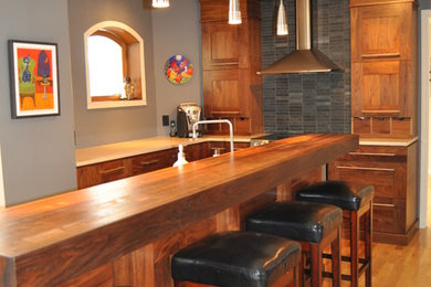 Example of a mid-sized trendy l-shaped light wood floor and brown floor eat-in kitchen design in Montreal with an undermount sink, shaker cabinets, medium tone wood cabinets, quartz countertops, gray backsplash, stone tile backsplash, stainless steel appliances, an island and white countertops