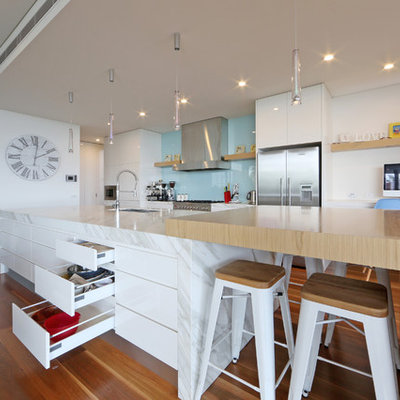 Kitchen - contemporary galley kitchen idea in Melbourne with an undermount sink, flat-panel cabinets, white cabinets, wood countertops, blue backsplash, glass sheet backsplash and stainless steel appliances