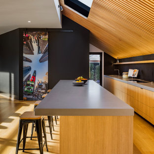 Large contemporary galley open plan kitchen in Melbourne with solid surface benchtops, with island, brown floor, grey benchtop, flat-panel cabinets, medium wood cabinets and medium hardwood floors.