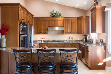 Ejemplo de cocina de estilo americano con armarios con paneles con relieve, electrodomésticos de acero inoxidable y península