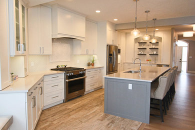 Eat-in kitchen - mid-sized transitional galley porcelain tile and brown floor eat-in kitchen idea in Calgary with an undermount sink, shaker cabinets, white cabinets, quartz countertops, gray backsplash, porcelain backsplash, stainless steel appliances and an island