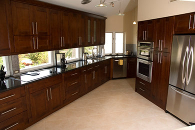 Mid-sized transitional u-shaped travertine floor and beige floor eat-in kitchen photo in Orlando with a double-bowl sink, shaker cabinets, dark wood cabinets, mosaic tile backsplash, stainless steel appliances, an island, solid surface countertops and gray backsplash