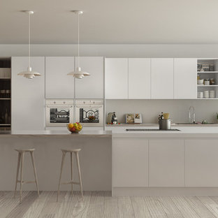 Foto de cocina lineal, moderna, de tamaño medio, cerrada, con fregadero encastrado, armarios con puertas mallorquinas, puertas de armario blancas, encimera de madera, salpicadero blanco, salpicadero de azulejos de porcelana, electrodomésticos de acero inoxidable, suelo de madera clara, una isla y suelo beige