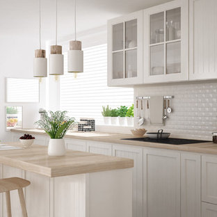 This is an example of a mid-sized shabby-chic style single-wall separate kitchen in Miami with a drop-in sink, louvered cabinets, white cabinets, wood benchtops, white splashback, porcelain splashback, stainless steel appliances, light hardwood floors, with island and beige floor.
