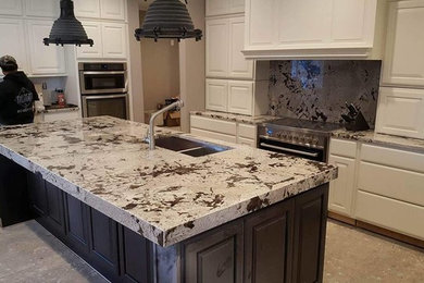 Inspiration for a large transitional u-shaped kitchen remodel in Chicago with raised-panel cabinets, white cabinets, granite countertops, stone slab backsplash, stainless steel appliances and an island