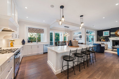 Inspiration for a large transitional l-shaped medium tone wood floor and brown floor eat-in kitchen remodel in Vancouver with an undermount sink, shaker cabinets, white cabinets, quartz countertops, white backsplash, glass tile backsplash, stainless steel appliances and an island