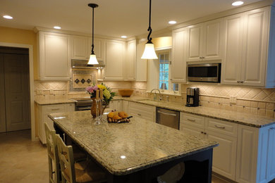 Inspiration for a mid-sized transitional l-shaped ceramic tile and beige floor open concept kitchen remodel in Boston with an undermount sink, raised-panel cabinets, white cabinets, granite countertops, beige backsplash, ceramic backsplash, stainless steel appliances and an island
