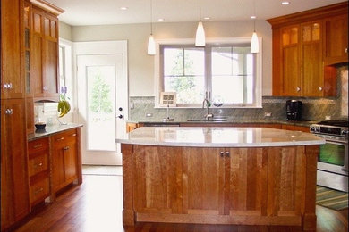 Kitchen pantry - large traditional u-shaped medium tone wood floor kitchen pantry idea in Seattle with a double-bowl sink, glass-front cabinets, medium tone wood cabinets, marble countertops, green backsplash, stainless steel appliances and an island