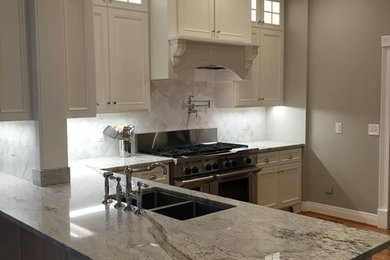 Trendy l-shaped medium tone wood floor enclosed kitchen photo in Nashville with a double-bowl sink, recessed-panel cabinets, white cabinets, white backsplash, stainless steel appliances and a peninsula