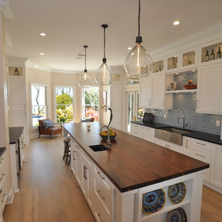 This is an example of a large transitional galley eat-in kitchen in Tampa with a farmhouse sink, shaker cabinets, white cabinets, granite benchtops, blue splashback, subway tile splashback, stainless steel appliances, medium hardwood floors and with island.