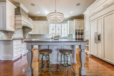 Inspiration for a large timeless u-shaped dark wood floor, brown floor and vaulted ceiling eat-in kitchen remodel in Dallas with an undermount sink, recessed-panel cabinets, white cabinets, soapstone countertops, gray backsplash, subway tile backsplash, paneled appliances, an island and gray countertops