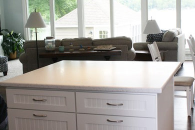 Example of a mid-sized beach style l-shaped kitchen design in Milwaukee with an undermount sink, shaker cabinets, white cabinets, solid surface countertops, stainless steel appliances and an island