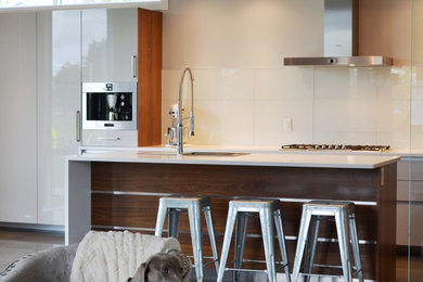 Mid-sized trendy single-wall eat-in kitchen photo in Ottawa with an undermount sink, flat-panel cabinets, white cabinets, solid surface countertops, white backsplash and an island