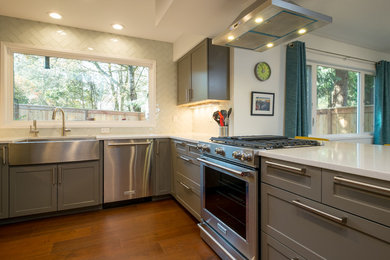 Eat-in kitchen - small contemporary u-shaped dark wood floor eat-in kitchen idea in Portland with a farmhouse sink, shaker cabinets, gray cabinets, quartz countertops, white backsplash, glass tile backsplash, stainless steel appliances and a peninsula