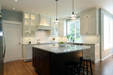 Open concept kitchen - mid-sized transitional u-shaped medium tone wood floor open concept kitchen idea in Portland with an undermount sink, recessed-panel cabinets, white cabinets, granite countertops, white backsplash, subway tile backsplash, stainless steel appliances and an island