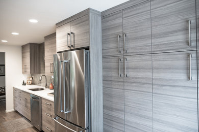 Small minimalist galley medium tone wood floor and brown floor kitchen pantry photo in Portland with a double-bowl sink, flat-panel cabinets, beige cabinets, quartz countertops, beige backsplash, ceramic backsplash, stainless steel appliances and no island
