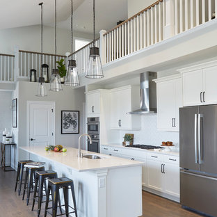 Immagine di una cucina lineare stile marino con ante bianche, top in quarzo composito, paraspruzzi bianco, elettrodomestici in acciaio inossidabile, pavimento in legno massello medio, isola, top bianco, lavello sottopiano e ante in stile shaker