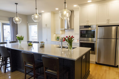 Example of a mid-sized transitional galley light wood floor eat-in kitchen design in Other with an undermount sink, shaker cabinets, white cabinets, quartz countertops, white backsplash, ceramic backsplash, stainless steel appliances and an island
