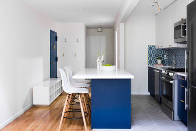 Mid-sized minimalist single-wall porcelain tile and gray floor open concept kitchen photo in New York with an undermount sink, flat-panel cabinets, blue cabinets, quartz countertops, blue backsplash, cement tile backsplash, stainless steel appliances, an island and white countertops