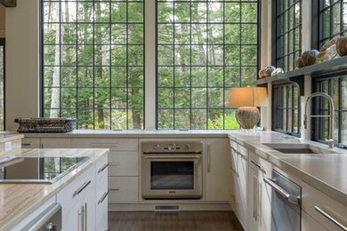 Eat-in kitchen - contemporary eat-in kitchen idea in Manchester with flat-panel cabinets, white cabinets, limestone countertops, stainless steel appliances and an island