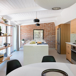 Photo of a mid-sized midcentury galley open plan kitchen in Other with an undermount sink, flat-panel cabinets, medium wood cabinets, quartz benchtops, green splashback, ceramic splashback, stainless steel appliances, porcelain floors, with island and grey floor.