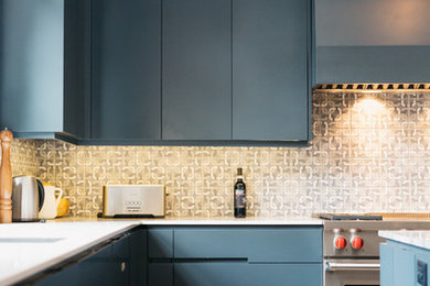 Immagine di una cucina industriale con ante lisce, ante blu, paraspruzzi con piastrelle di cemento, elettrodomestici in acciaio inossidabile e parquet chiaro