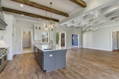 Example of a mid-sized cottage single-wall dark wood floor and brown floor eat-in kitchen design in New Orleans with a farmhouse sink, shaker cabinets, white cabinets, quartz countertops, multicolored backsplash, stone tile backsplash, an island and white countertops