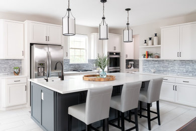 Example of a transitional l-shaped white floor kitchen design in Austin with an undermount sink, recessed-panel cabinets, gray backsplash, stainless steel appliances, an island and white countertops