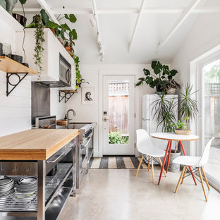 Immagine di una piccola cucina costiera con top in legno, paraspruzzi bianco, paraspruzzi in legno, pavimento in cemento, elettrodomestici in acciaio inossidabile e pavimento grigio