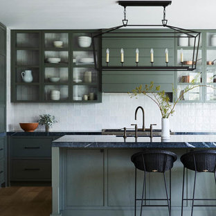 Inspiration for a transitional l-shaped kitchen in Sydney with flat-panel cabinets, green cabinets, white splashback, stainless steel appliances, light hardwood floors, with island, beige floor and black benchtop.