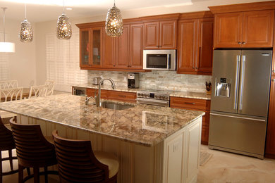 Example of a mid-sized classic single-wall beige floor eat-in kitchen design in Miami with an undermount sink, raised-panel cabinets, medium tone wood cabinets, granite countertops, gray backsplash, stone tile backsplash, stainless steel appliances, an island and gray countertops