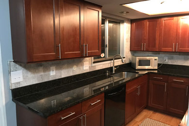 Inspiration for a mid-sized transitional l-shaped light wood floor and brown floor enclosed kitchen remodel in Birmingham with an undermount sink, recessed-panel cabinets, dark wood cabinets, quartz countertops, gray backsplash, porcelain backsplash, stainless steel appliances, an island and black countertops