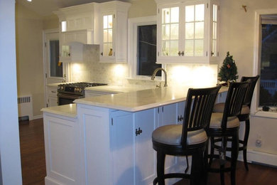 Mid-sized elegant medium tone wood floor kitchen photo in New York with an undermount sink, beaded inset cabinets, white cabinets, quartz countertops, stone tile backsplash and stainless steel appliances