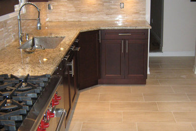 Eat-in kitchen - large transitional l-shaped ceramic tile eat-in kitchen idea in Toronto with an undermount sink, raised-panel cabinets, granite countertops, beige backsplash, glass tile backsplash, stainless steel appliances and an island