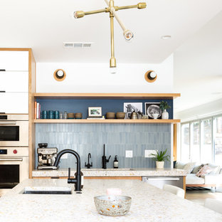 Large midcentury galley open plan kitchen in Los Angeles with an undermount sink, flat-panel cabinets, blue cabinets, concrete benchtops, blue splashback, ceramic splashback, stainless steel appliances, light hardwood floors and with island.