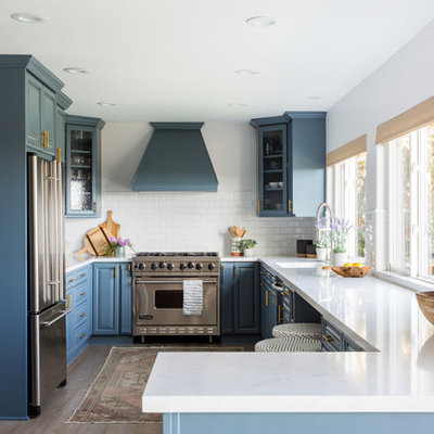 Kitchen - coastal u-shaped kitchen idea in Los Angeles with a single-bowl sink, raised-panel cabinets, blue cabinets, white backsplash, subway tile backsplash, stainless steel appliances, a peninsula and white countertops