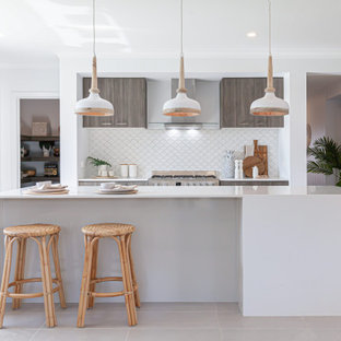 This is an example of a mid-sized tropical galley open plan kitchen in Melbourne with an undermount sink, quartz benchtops, white splashback, ceramic splashback, stainless steel appliances, ceramic floors, with island, beige floor and yellow benchtop.