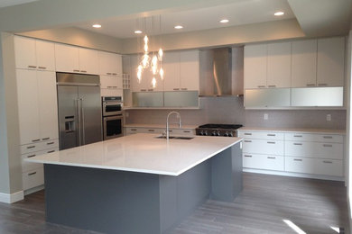 Enclosed kitchen - mid-sized contemporary l-shaped light wood floor and gray floor enclosed kitchen idea in Edmonton with a double-bowl sink, flat-panel cabinets, white cabinets, solid surface countertops, gray backsplash, mosaic tile backsplash, stainless steel appliances and an island