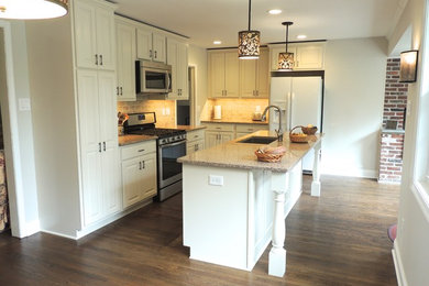 Example of a mid-sized classic medium tone wood floor eat-in kitchen design in Philadelphia with a single-bowl sink, raised-panel cabinets, white cabinets, quartzite countertops, beige backsplash, ceramic backsplash, stainless steel appliances and an island